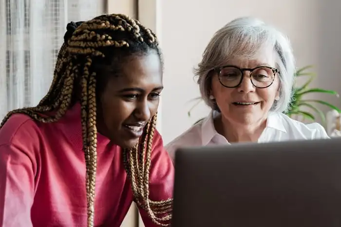 Young person and older person gazing at a laptop screen.
