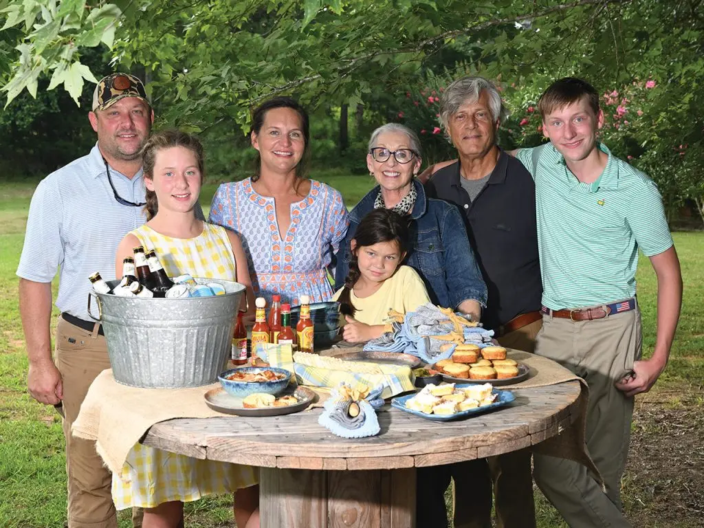 Family posing for a picture together behind a table full of Southern-style food