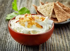 bowl of cream cheese with caramelized onions on wooden table