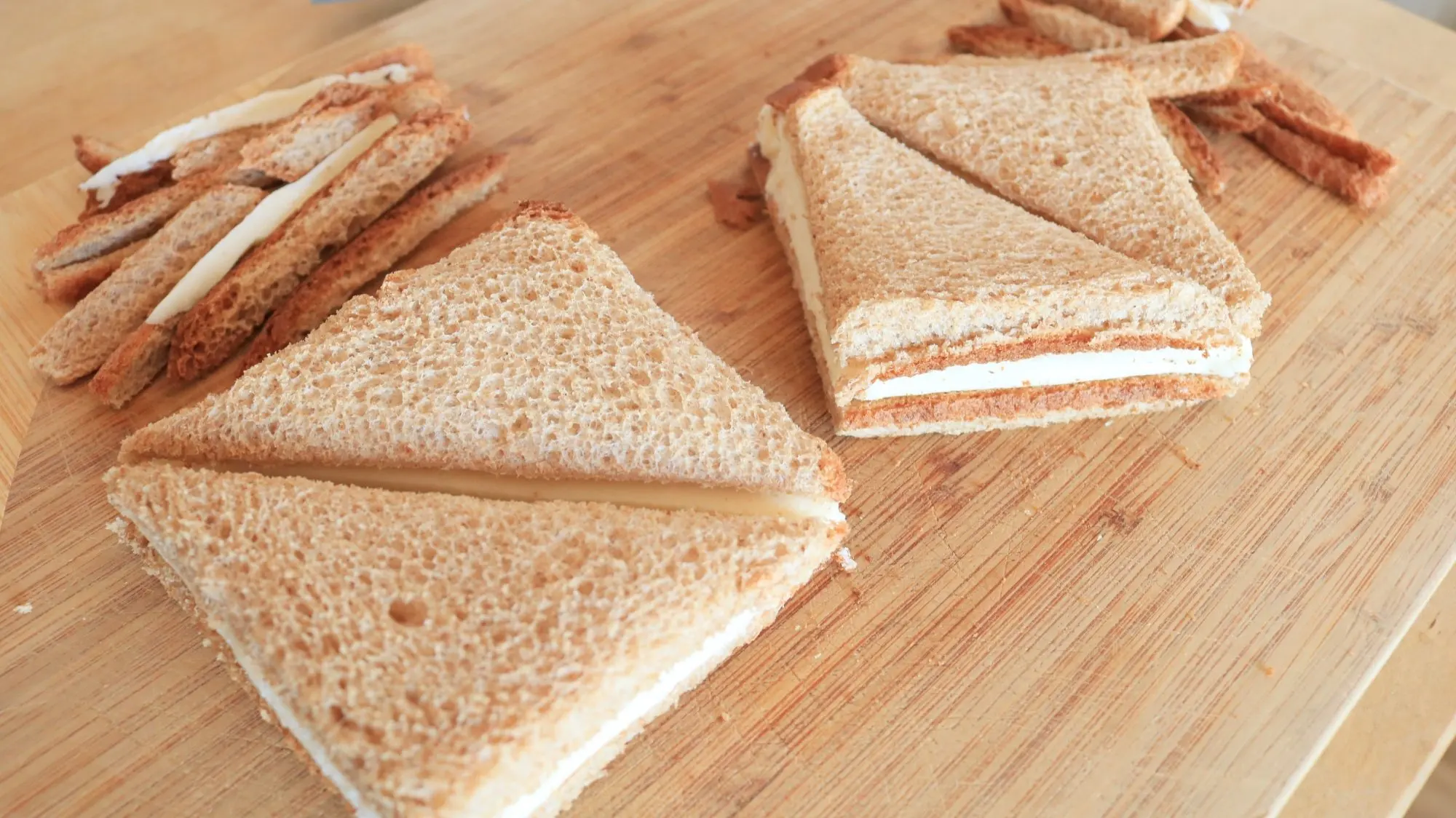 Two cheese sandwiches with crusts trimmed off.