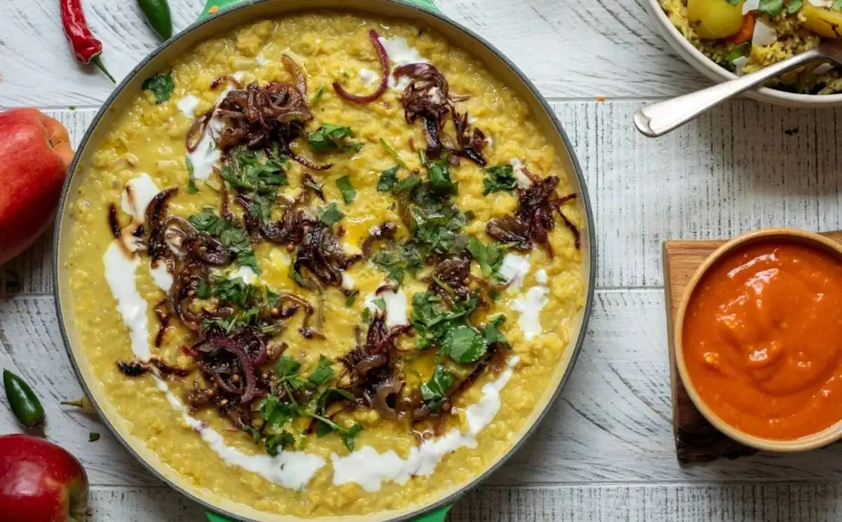 Photo shows a large bowl of apple and coconut dhal topped with floral garnish