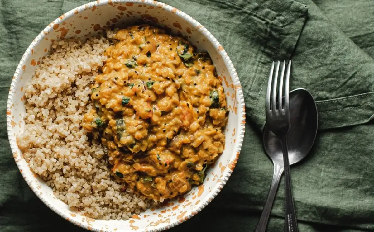 Photo shows a white bowl of butternut squash dhal served with quinoa