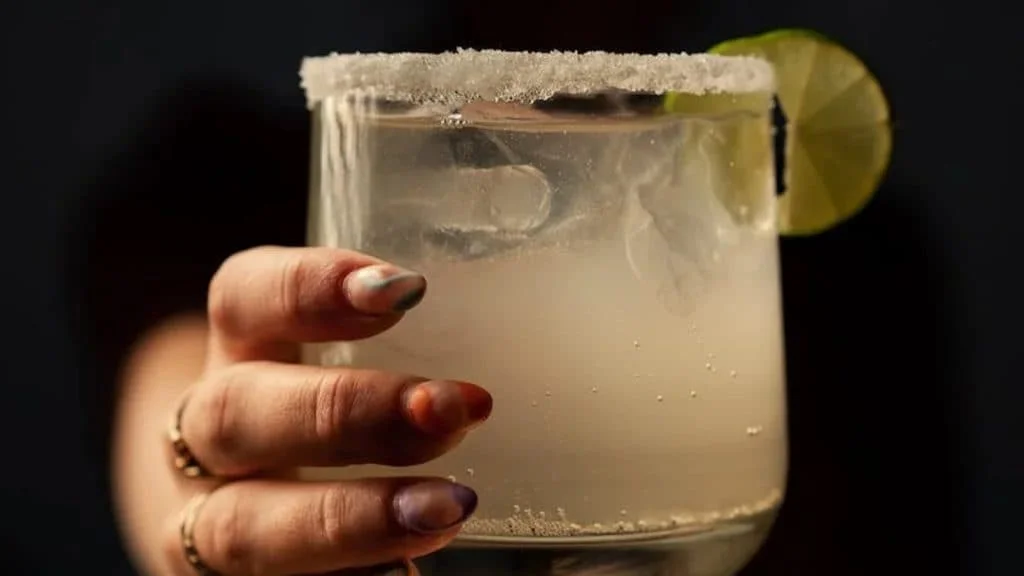 A hand holding a margarita on the rocks