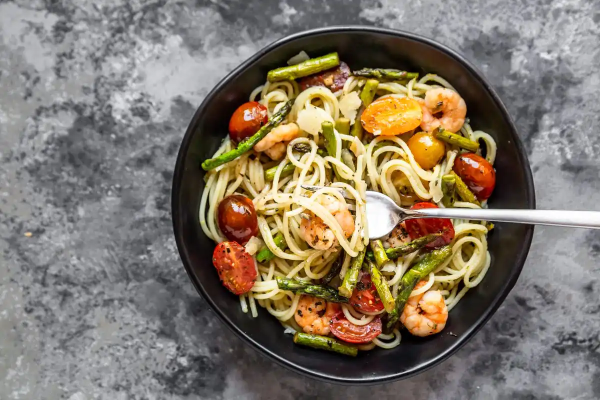 Bowl of spaghetti with shrimp, asparagus, tomatoes and pesto