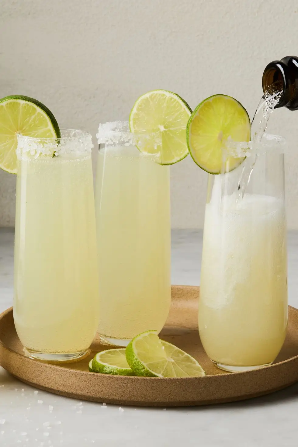 champagne margaritas in flutes rimmed with salt and a lime wheel