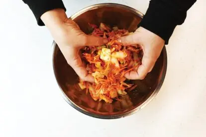 mixing vegan kimchi paste into cabbage