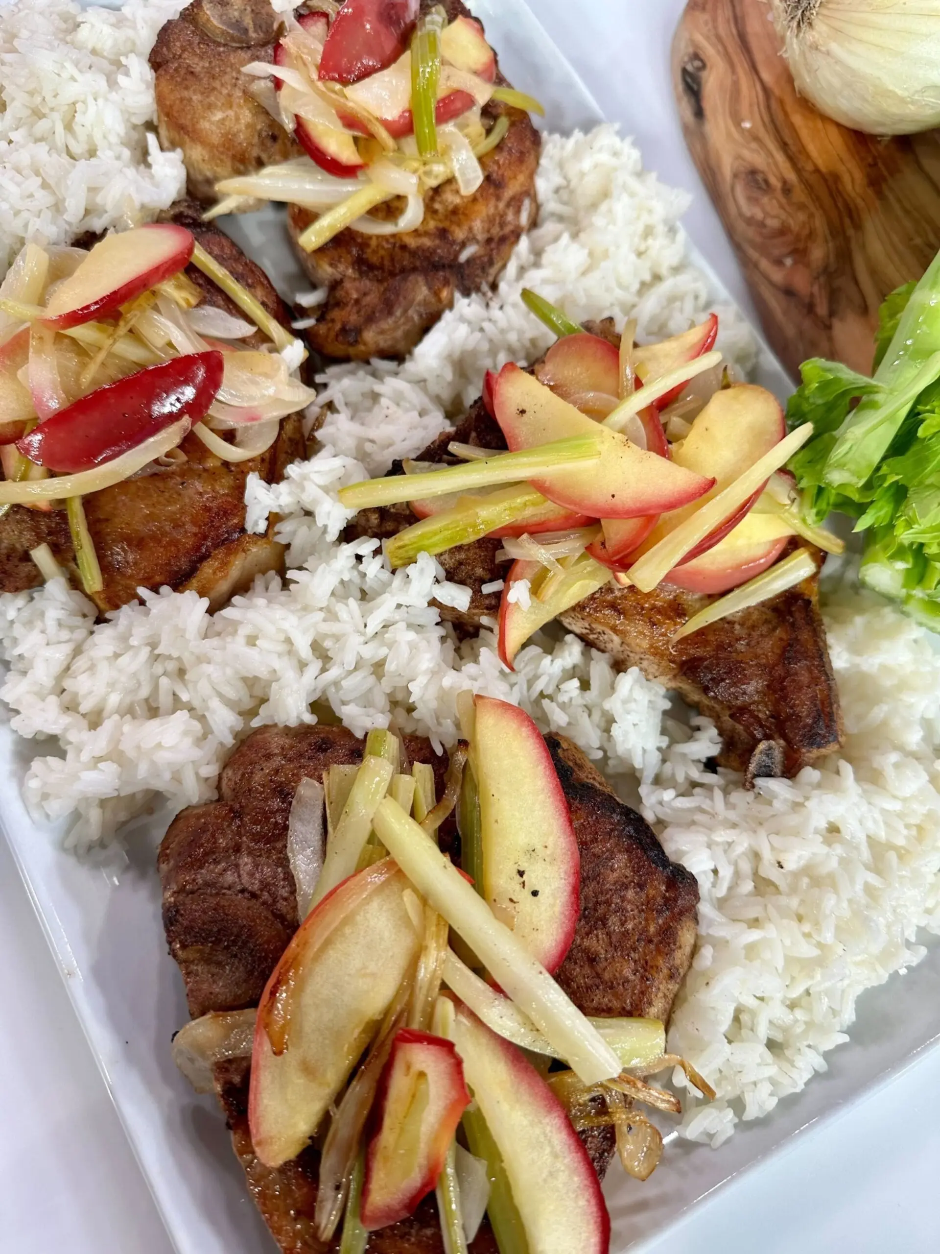 PHOTO: A plate of pork over rice topped with apples.