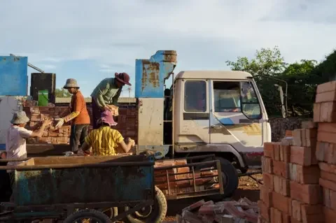 Thomas Cristofoletti/ BBC Workers load bricks on a truck in a kiln located in Kandal province.