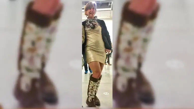 A smiling woman in a sparkling silver dress and white boots with donkeys.