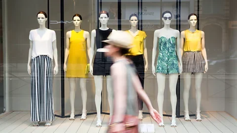 Getty Images Woman walks in front of store window ( Credit: Getty Images )