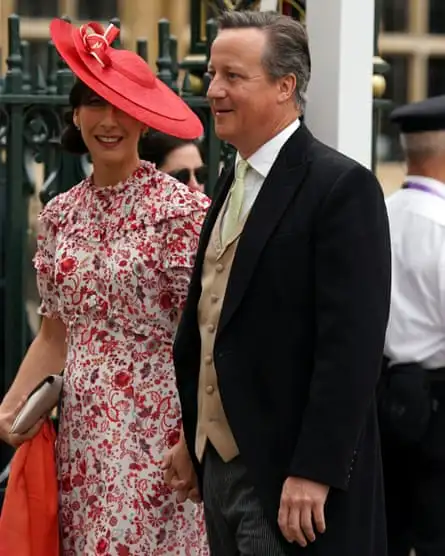 Samantha Cameron wearing a red hat standing next to David Cameron