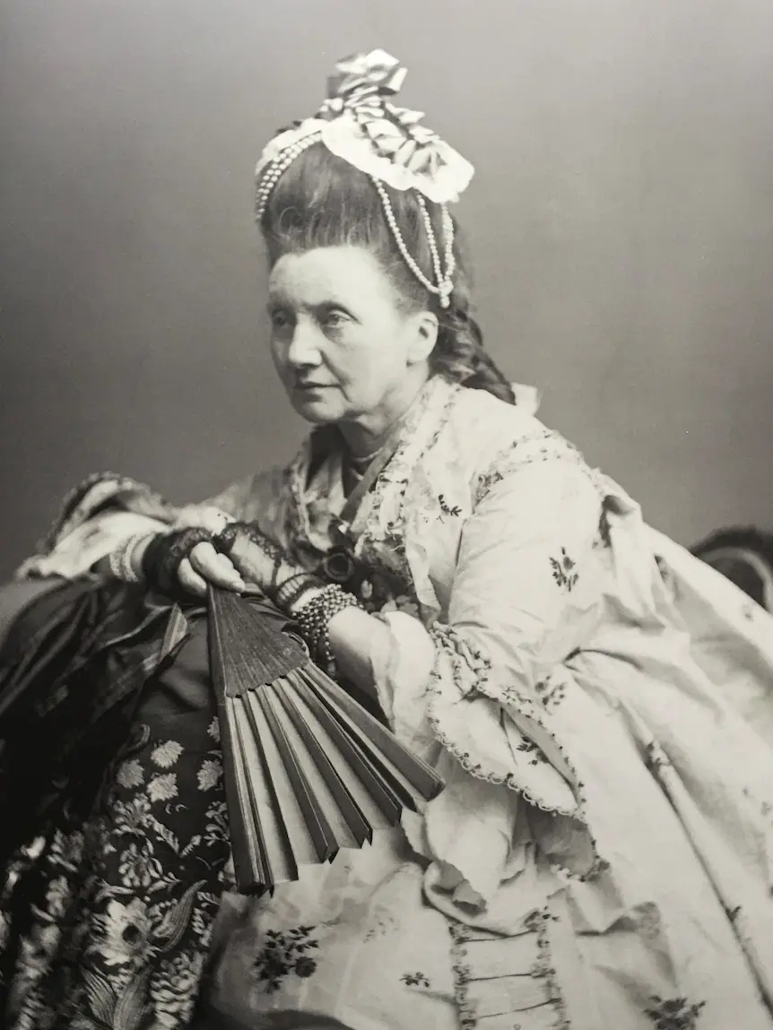 an old black and white photo of a lady in a gown