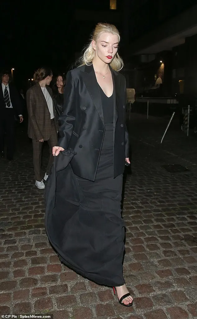 The 28-year-old donned a sleek black dress with a plunging neckline beneath a black longline tuxedo jacket and polished the look with a pair of black heeled sandals