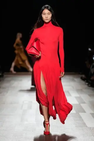 Ferragamo model wearing a red turtleneck drop-waist dress and carrying a red bag at the F/W 24 show.