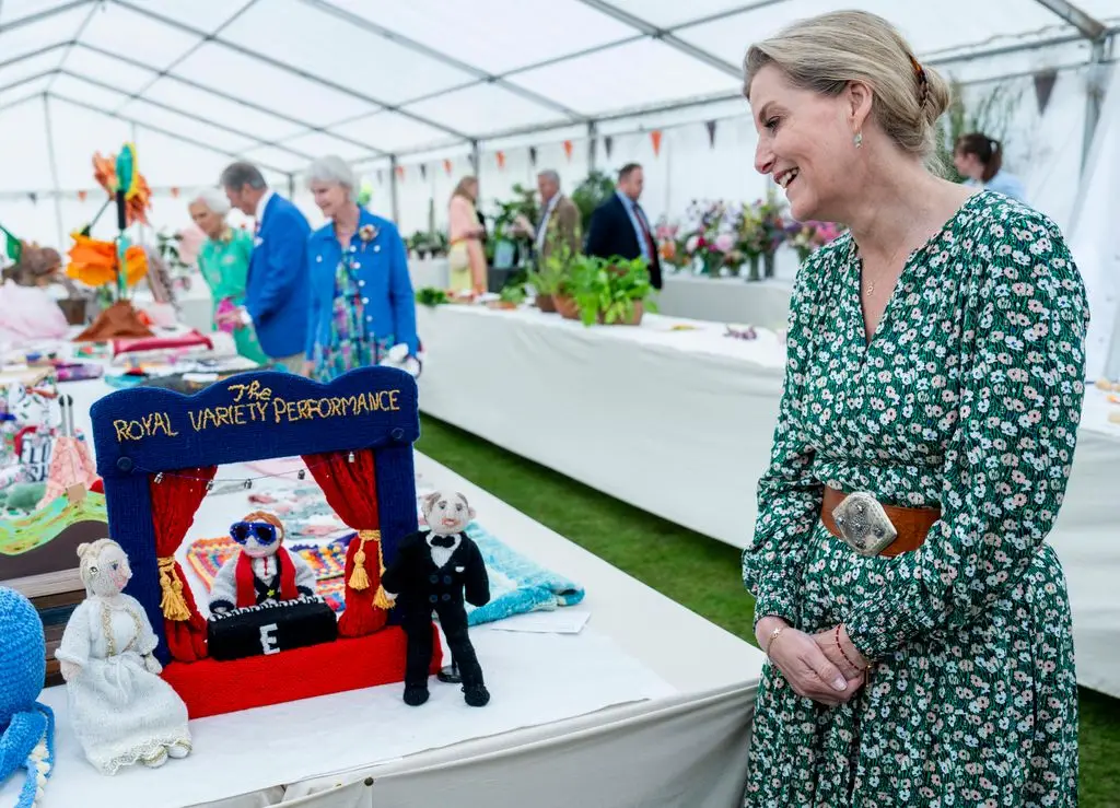 Duchess Sophie looking at a knitted version of herself, Prince Edward and Elton John