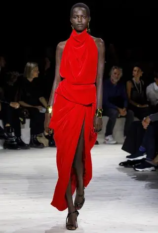 halter dress trend on the Alexander McQueen spring runway with a model wearing a red velvet dress styled with gold bangles and black sandals