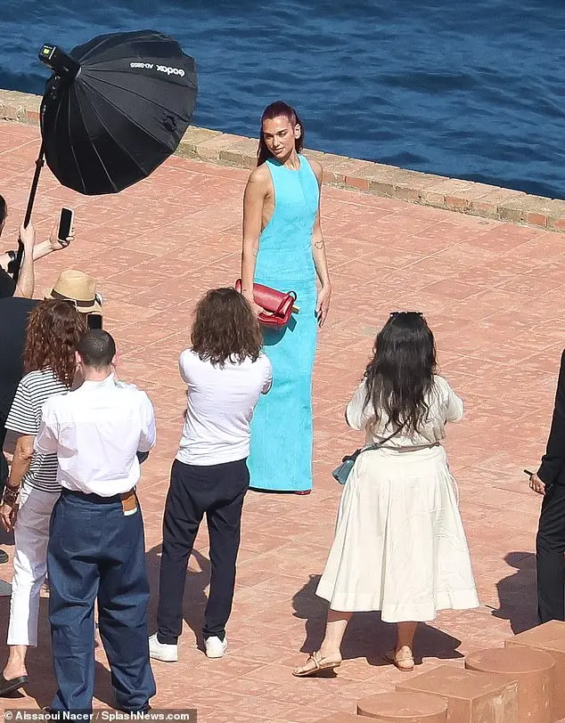 Dua Lipa looked stunning in a sky blue dress as she posed by the sea at the The Jacquemus Fashion Show in Capri, Italy on Monday