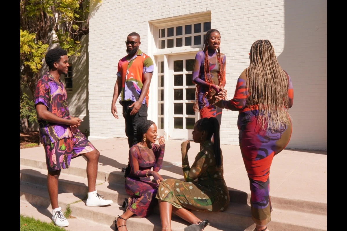 Models standing around casually dressed in colorful clothing.