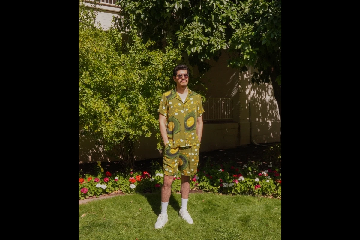 A male model stands wearing a colorful shorts and button-up shirt set.