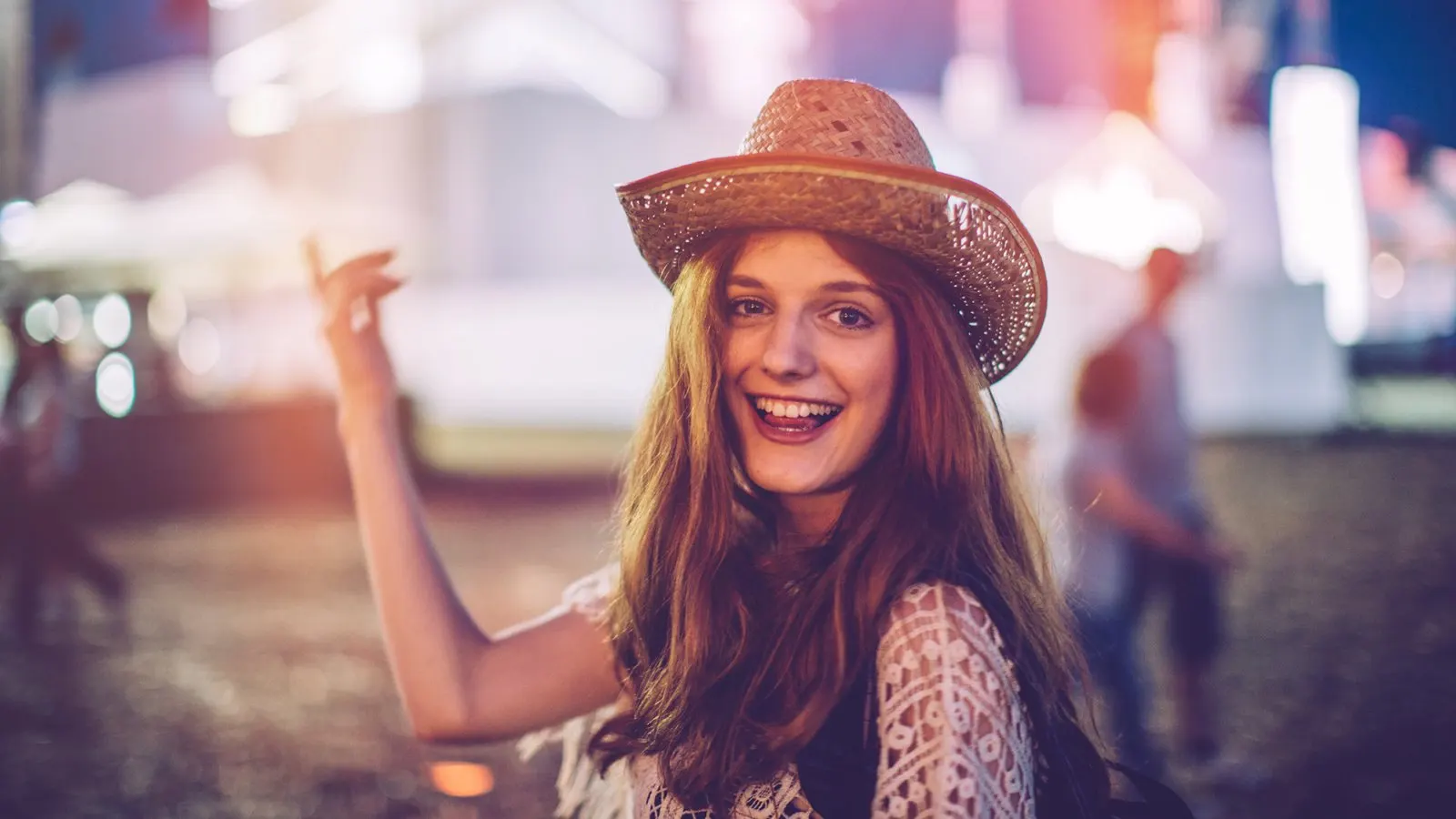 Young woman at summer festival. Dancing with her arms raised. Summertime.