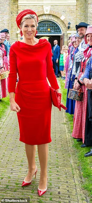 The queen smiled elegantly to have her picture taken next to locals wearing traditional Dutch dress