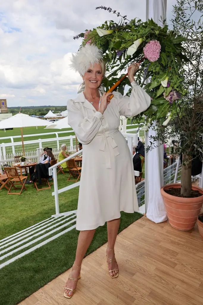 Penny Lancaster in a feathered fascinator and holding a floral parasol