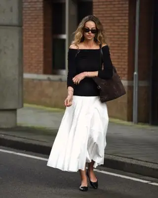 Woman wearing dress with black top and white full-length skirt.