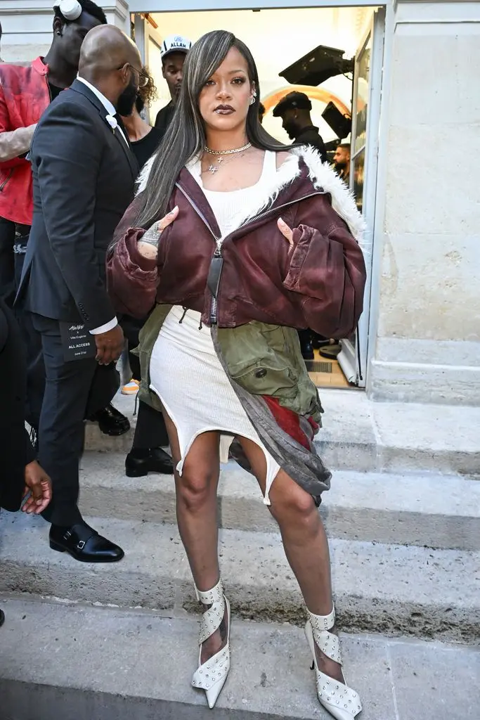 Rihanna on stairs in white dress and layered jackets