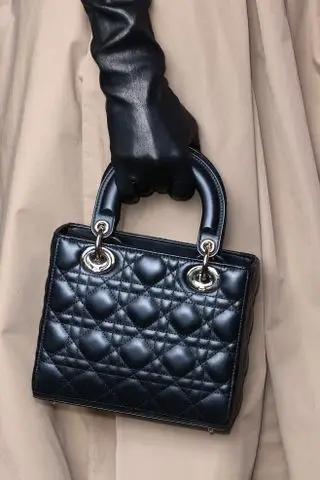 a close up of Jennifer Lopez carrying a black Lady Dior bag while leaving for the dior haute couture show