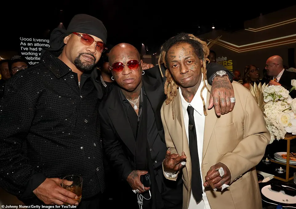 The 41-year-old hip-hop star (R, born Dwayne Carter Jr.) wore a tan suit as he mingled with fellow Hot Boys rapper Juvenile (L) and his mentor Birdman aka Bryan 'Baby Williams (M)