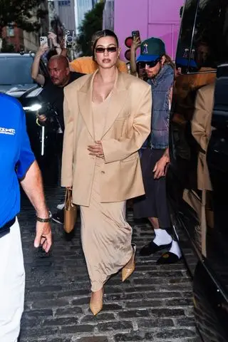 Hailey Bieber wears a jersey dress with pointed-toe heels, and a blazer.