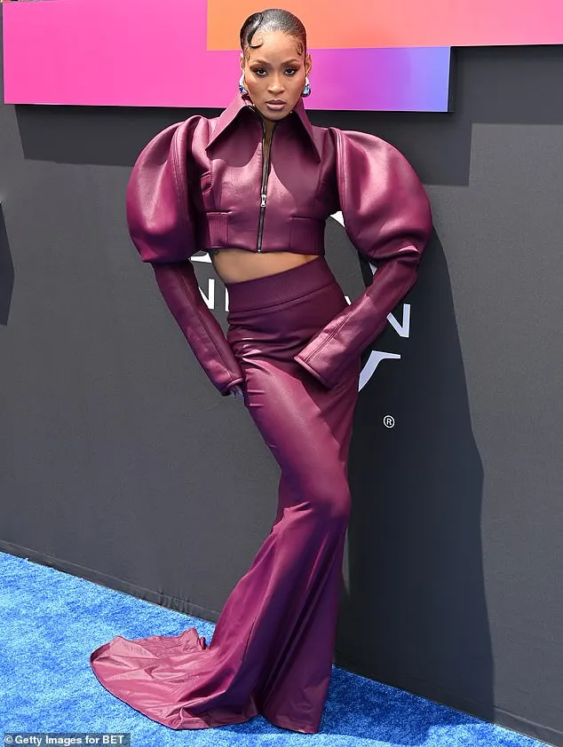 Pretty Vee opted for a bold outfit that comprised of a purple, leather cropped jacket with dramatic sleeves as well as a matching, fitted skirt that fell down towards the ground