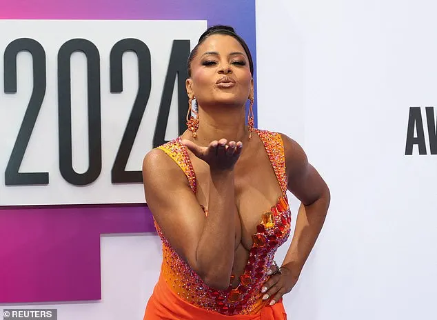 Claudia Jordan was seen blowing a kiss on the red carpet while wearing a bejeweled dress that contained various hues of orange, yellow and red