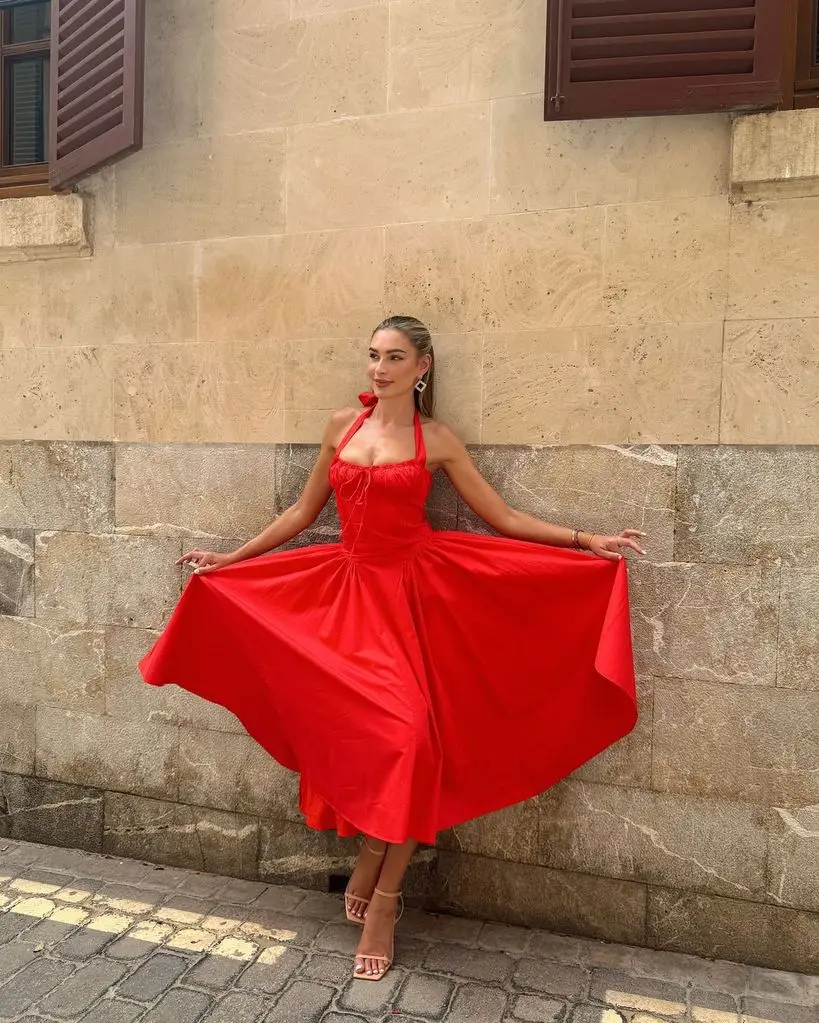 Zara McDermott poses against a wall in red dress in Majorca