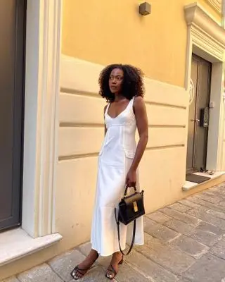 Influencer wears black shoes with a white dress.