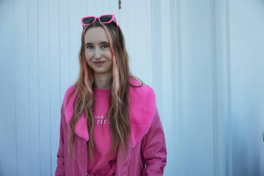 A woman named Ellise wearing pink clothing and smiling for the camera.