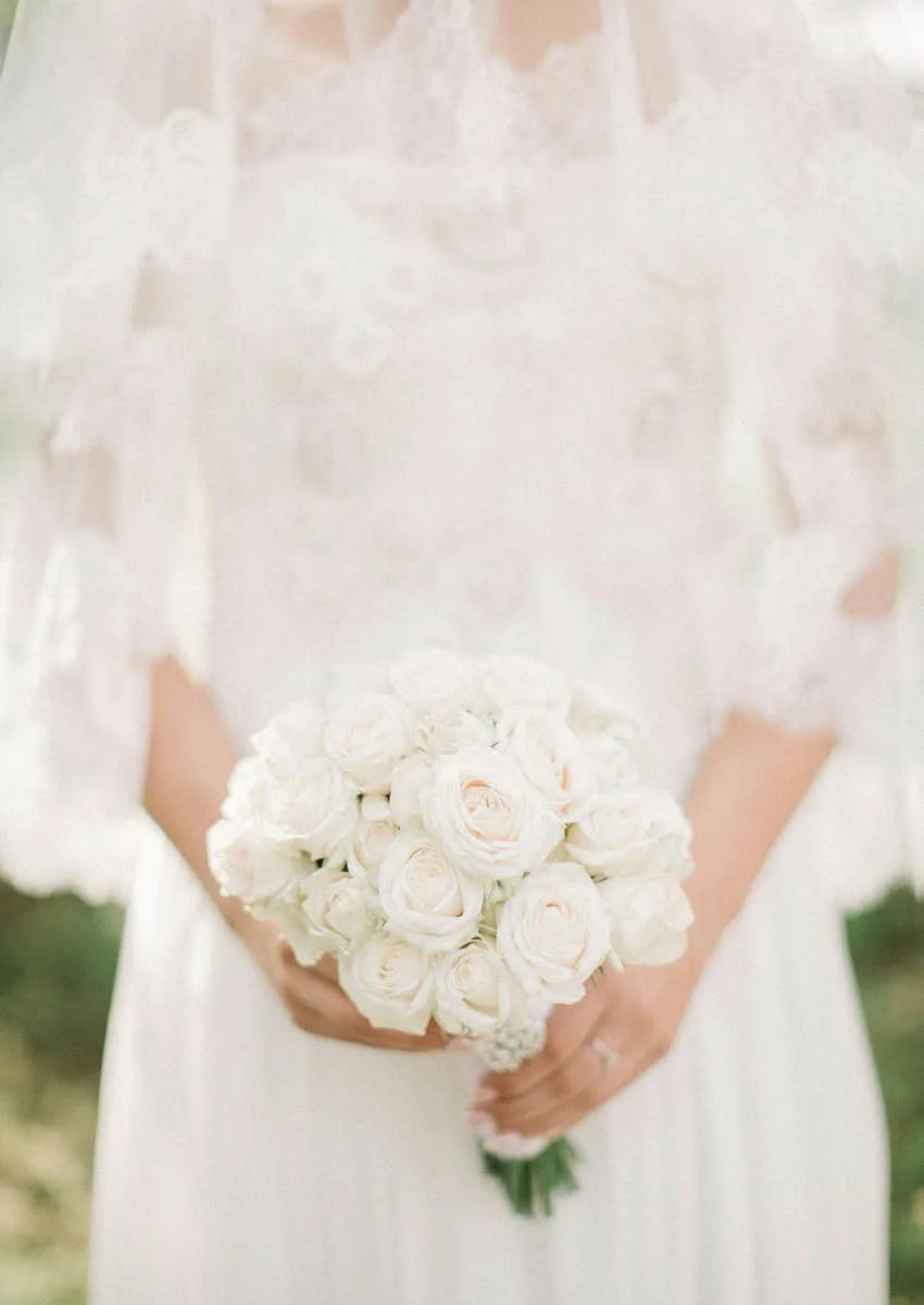 bride covered by veil holding flowers