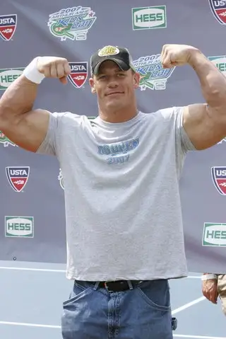 Image may contain John Cena Clothing TShirt Baseball Cap Cap Hat Adult Person Body Part Finger Hand and Baby