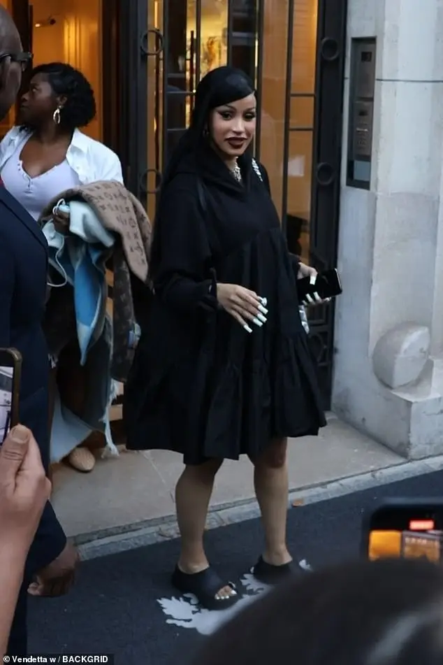 Cardi B covered up her curves in a black floaty dress and gothic makeup as she headed out for dinner in Paris on Wednesday evening