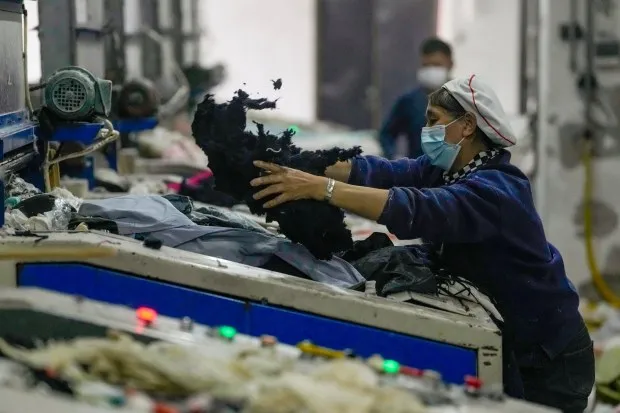 A worker feeds discarded textiles to a shredding machine at the Wenzhou Tiancheng Textile Company, one of China's largest cotton recycling plants in Wenzhou in eastern China's Zhejiang province on March 20, 2024. (AP Photo/Ng Han Guan)