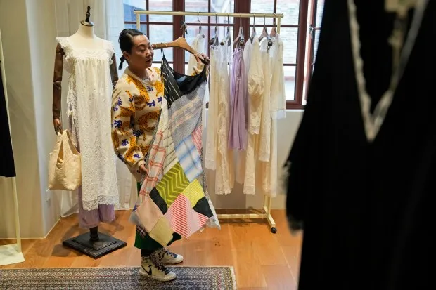 Zhang Na, whose fashion label, Reclothing Bank, sells clothes, bags and other accessories made from materials such as plastic bottles, fishing nets and flour sacks, look at some of the products during an interview at her store in Shanghai on March 19, 2024. ( AP Photo/Ng Han Guan )