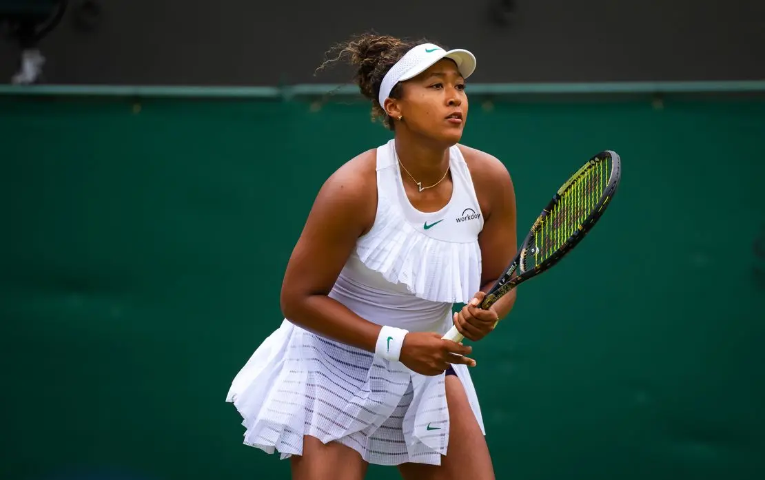 Naomi Osaka wore a flouncy take on the tennis dress at Wimbledon 2024, adhering to tournaments all-white, minimal logo rule — with an exception for dark-colored shorts, which is a new allowance for women.