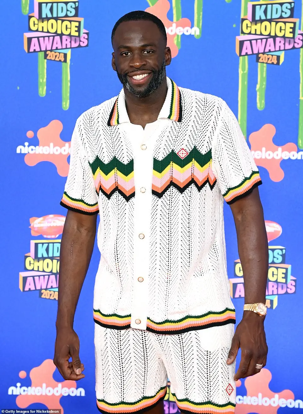 Draymond Green wore a white, knit shirt and matching shorts that contained a trim with hues of green, yellow, pink, and black