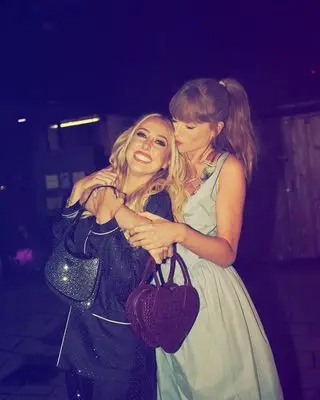 Taylor Swift with Brittany Mahomes wearing a blue Vivienne Westwood dress and carrying a heart-shaped bag