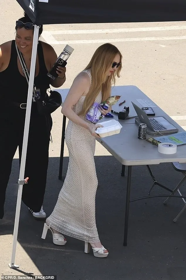 Lindsay Lohan cut a stylish figure in a sparkly long dress on Monday on the set of Freaky Friday 2, as she took a break in between filming for the highly-anticipated sequel in Los Angeles