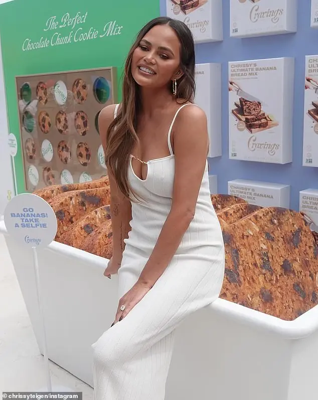 Chrissy Teigen kept her cool in a sexy white maxi dress while promoting her Cravings by Chrissy baking mixes in Chicago over the weekend. The figure hugging frock with low keyhole neck connected by a thin gold chain