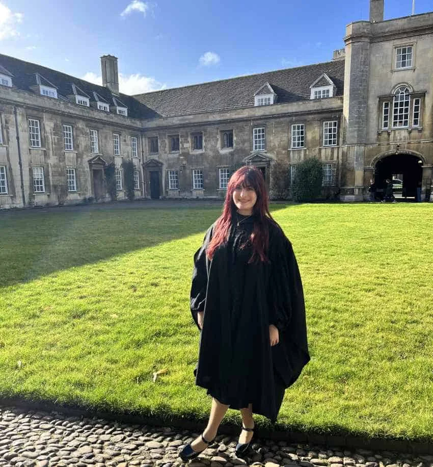 Woman in academic robes on college green