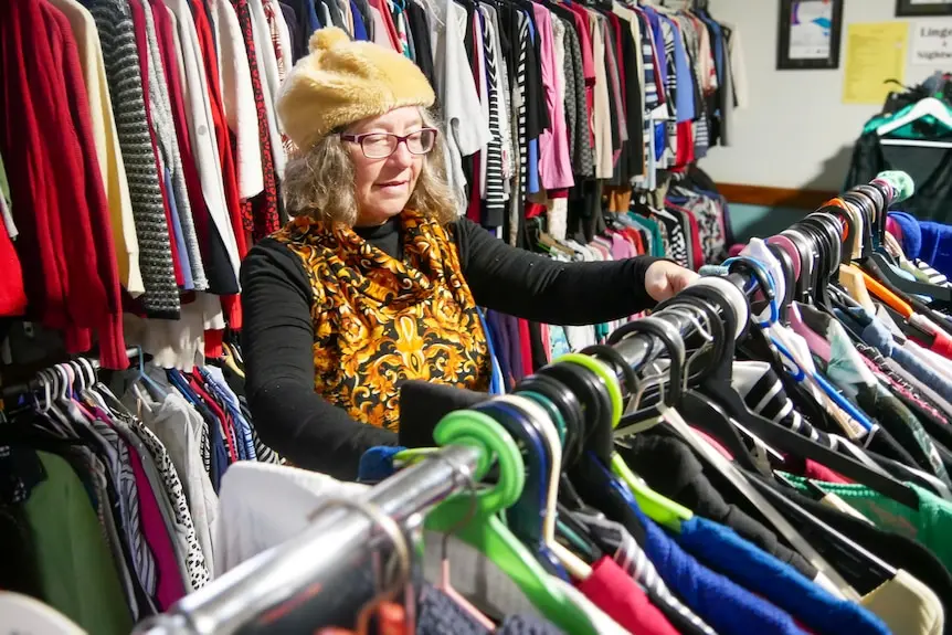 A woman looking through clothing racks at an op shop.