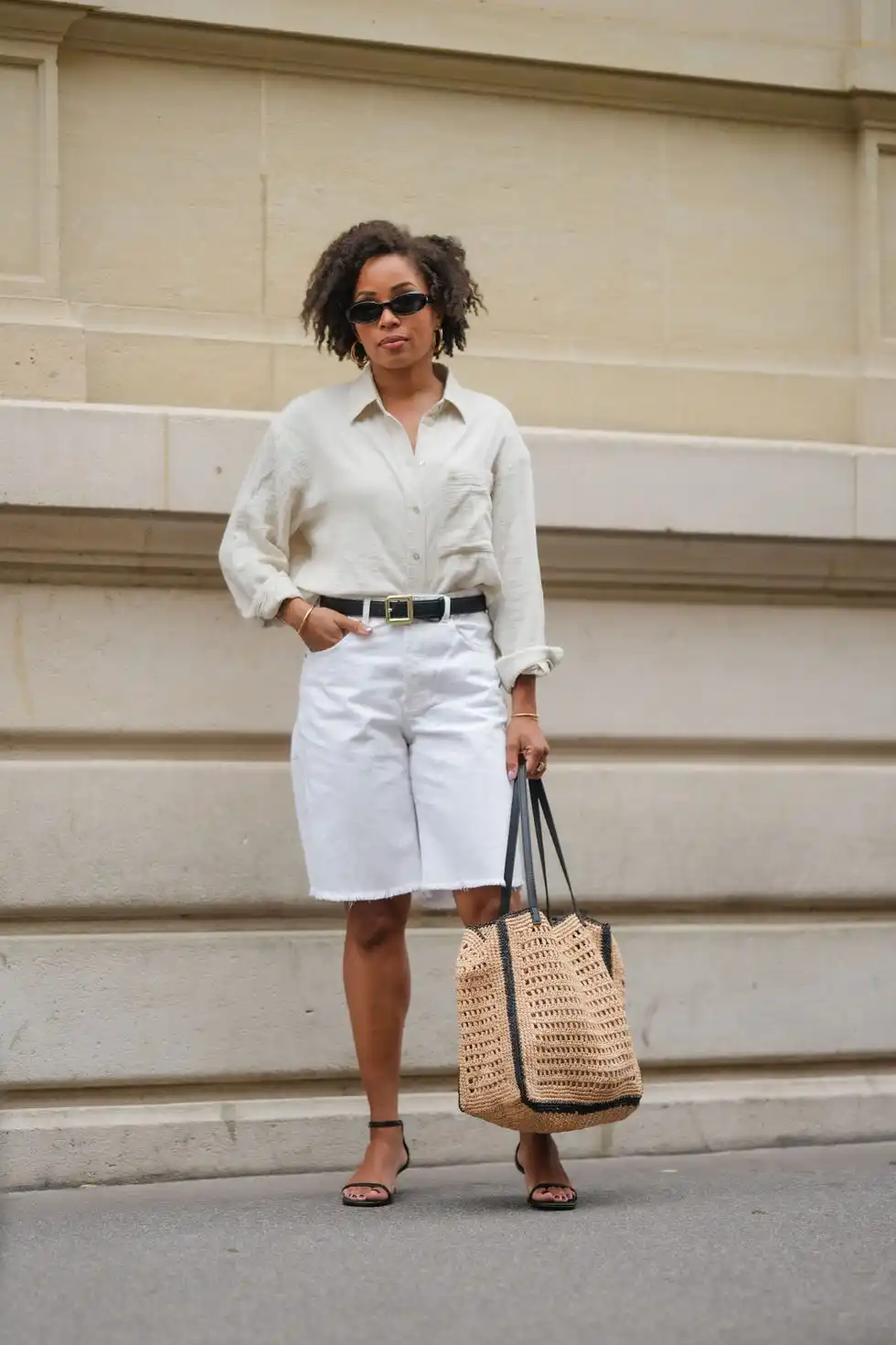 paris, france may 08 ellie delphine wears a full mango look, sunglasses, golden earrings, a white linen shirt, a black leather belt with golden buckle, golden bracelets, a white ripped denim shorts, a large brown raffia bag, black sandals, during a street style fashion photo session, on may 08, 2024 in paris, france photo by edward berthelotgetty images