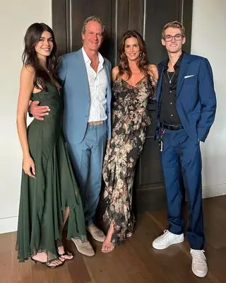 Kaia Gerber and Cindy Crawford stand with their family in a wedding guest photo